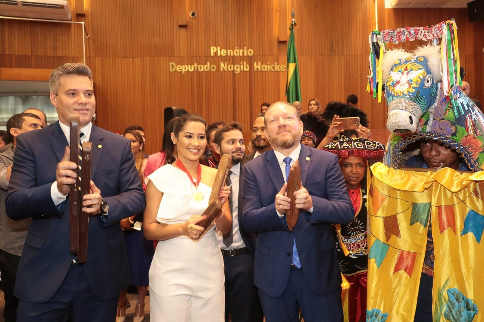 Thaynara OG e os deputados Neto Evangelista e Othelino acompanham a apresentação do Boi da Maioba na solenidade