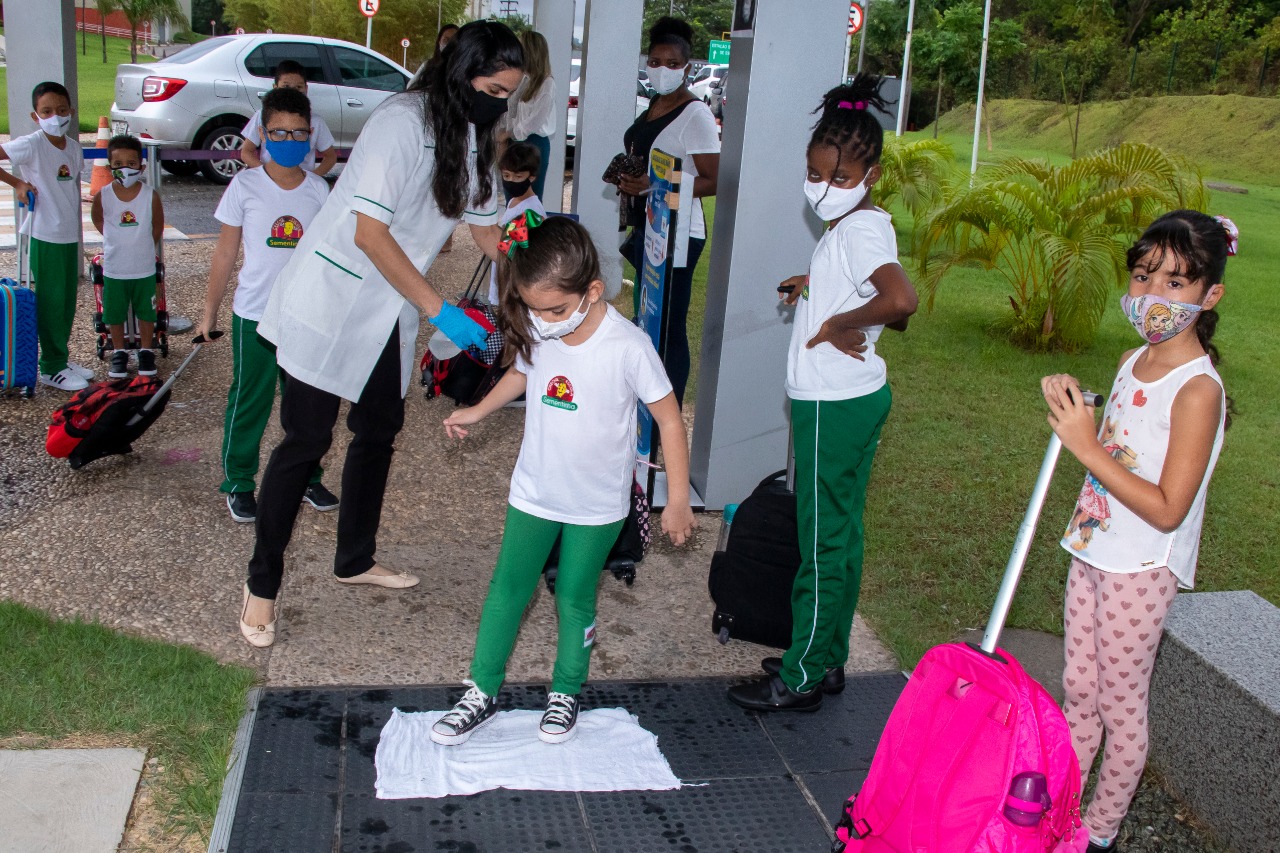 Aluna pisa em tapete sanitizante antes de entrar no prédio da creche-escola 