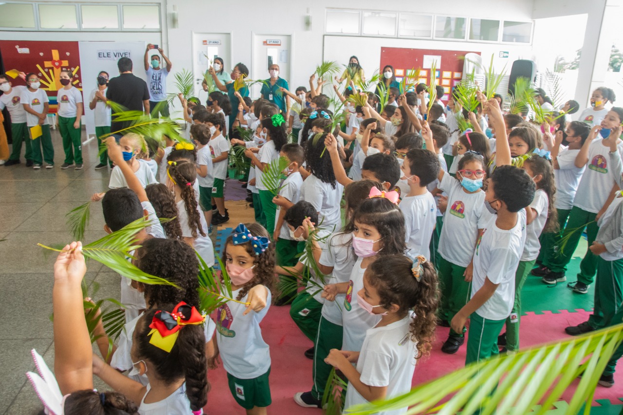 Alunos seguram ramos de palmeira durante uma das cenas da Via Sacra encenada por alunos da "Sementinha"