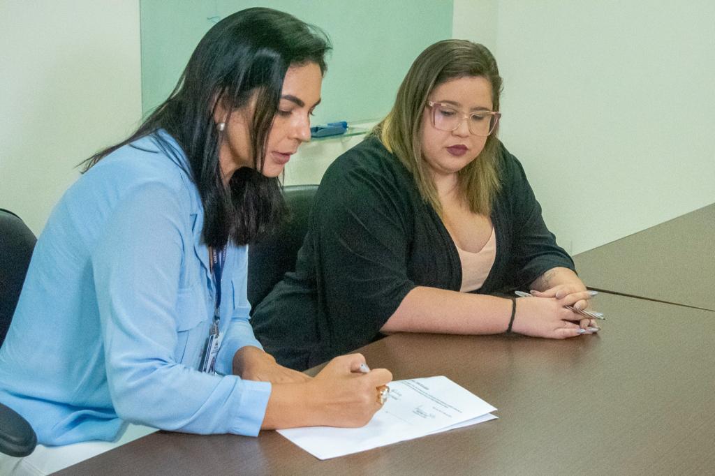 Silvana Leal, diretora de Desenvolvimento Social da Alema, assina o convênio, ao lado da secretária acadêmica Manuela Lima