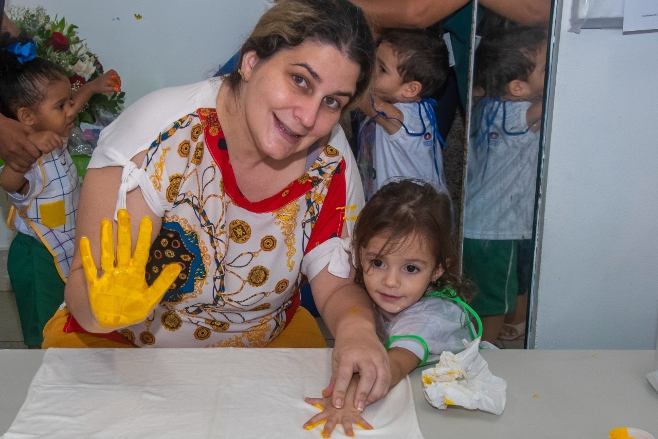 Mãe e filha na atividade “Pintando o Sete com a Mamãe”, onde ilustram a palma de suas mãos numa camisa 